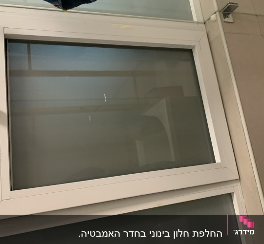 חלון זכוכית עם מסגרת לבנה וקיר בצד